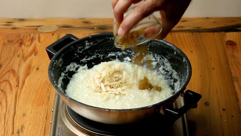 Add raisins (kishmish) and almonds to the reduced and thickened milk-sugar-coconut mixture - Karanji Recipe