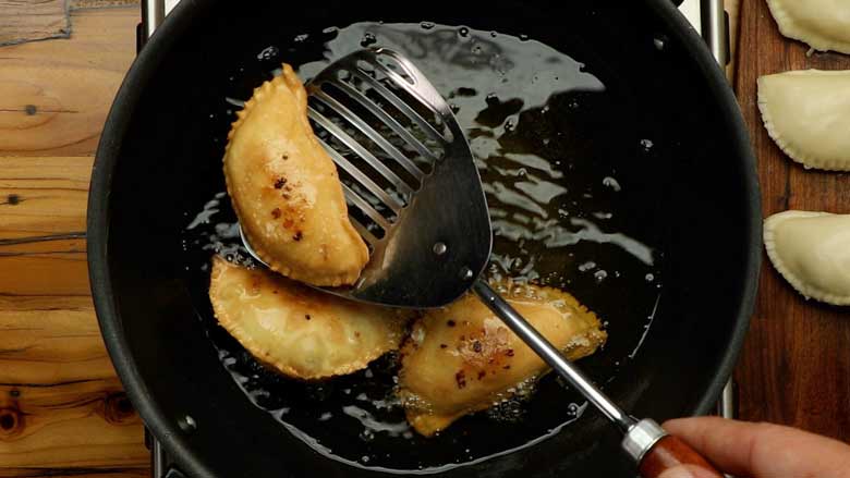 Remove golden brown karanjis from the ghee and set aside on kitchen paper to drain - Karanji Recipe