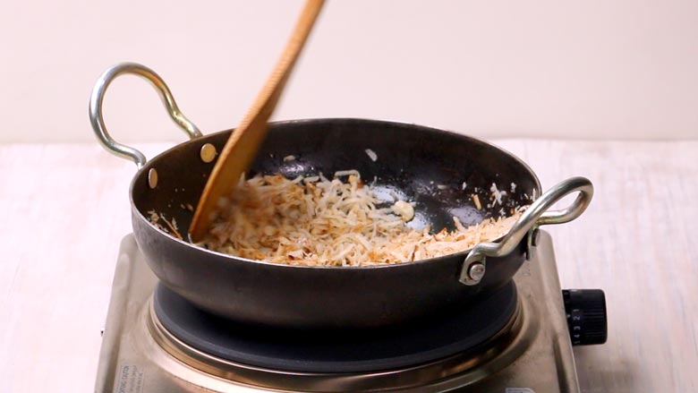 Stir fry garlic and dried coconut till golden for sukha masala (red garlic chutney) - Vada Pav Recipe