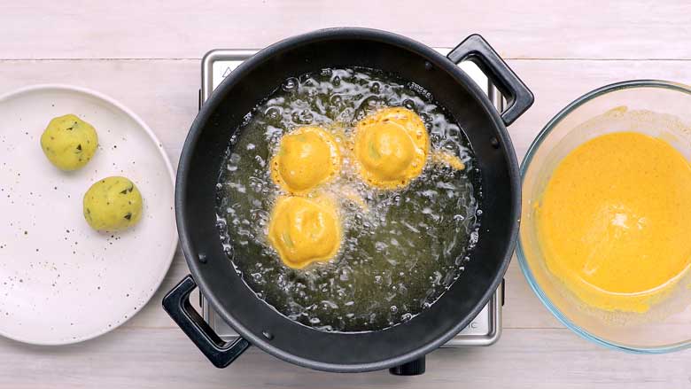 Dip the potato vada in the batter and place carefully in hot oil to fry - Vada Pav Recipe