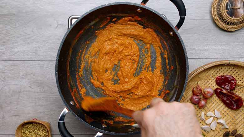 Thicken coconut cream in a wok then add khao suey paste and cook till thick and fragrant - Khao Soi Recipe - Chiang Mai Curried Noodles