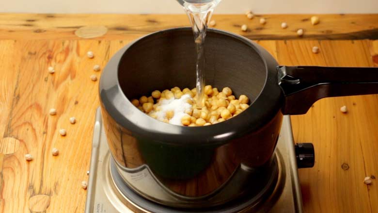 Place soaked chickpeas in a pressure cooker along with salty and baking soda. Add water and cook - Chana Gashi Recipe