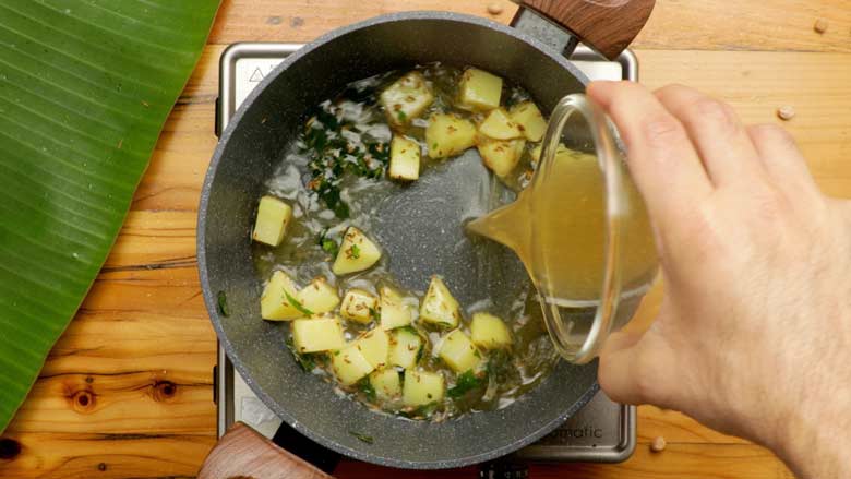 Add reserved chickpea cooking water to the potatoes - Chana Ghashi Recipe