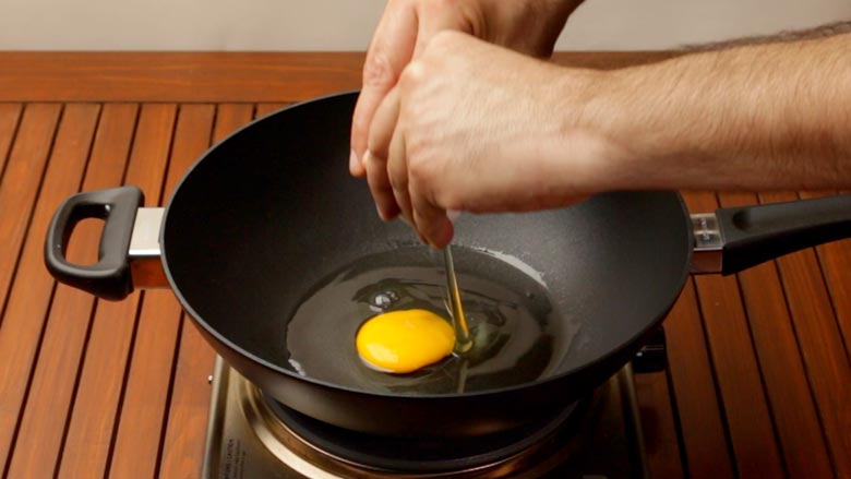 Heat oil and break egg into it - Nasi Goreng Recipe