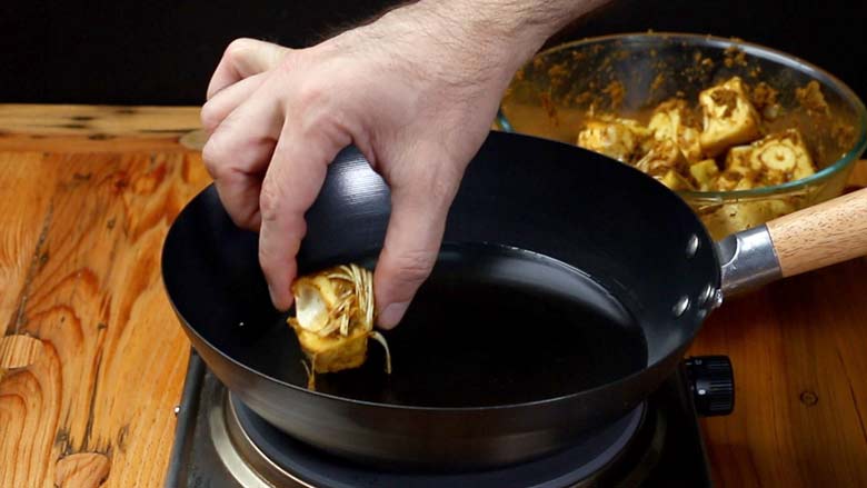 Heat oil in a kadhai or wok and carefully place marinated cubes of kathal (jackfruit) in the hot oil - Jackfruit Biryani Kathal Biryani Recipe