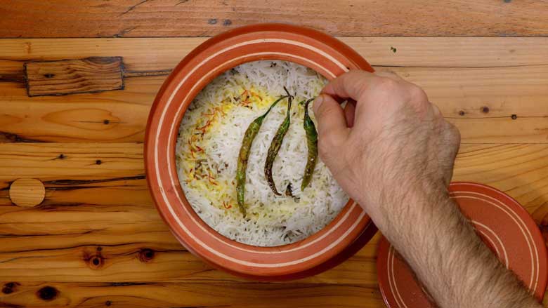 Pour on ghee, soaked saffron in milk, and place 3 fried green chillies on top before placing on dum - Jackfruit Biryani Kathal Biryani Recipe