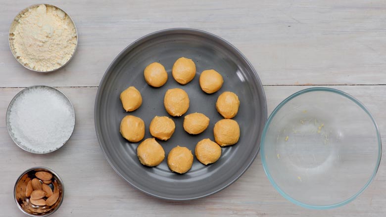 Keep placing besan ladoos on a greased plate or thali - Besan Ladoo Recipe