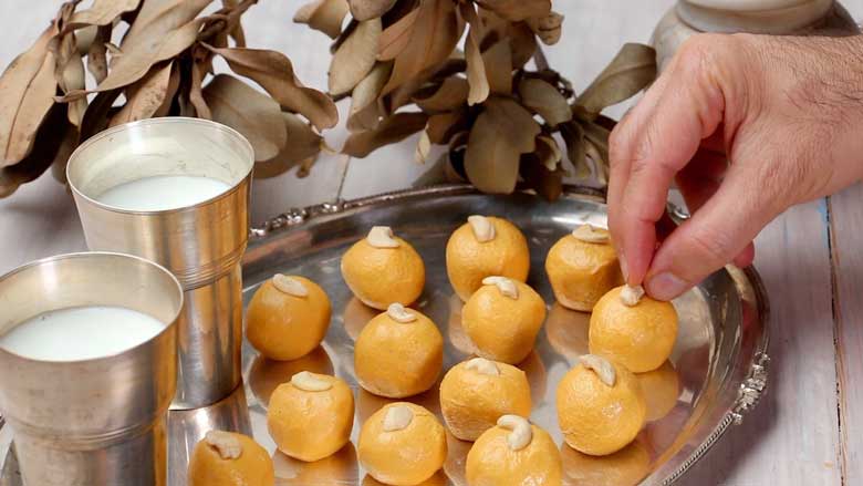 Garnish ladoos by lightly pressing a half cashew nut onto the top of each besan ladoo - Besan Ladoo Recipe