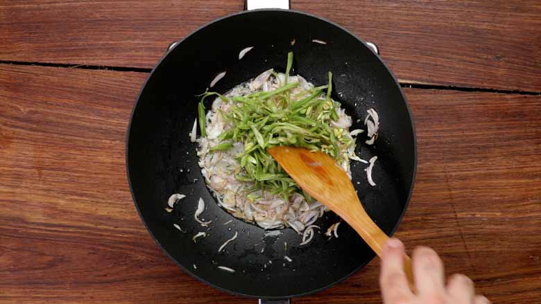 Add oil to a hot wok and stir fry onion, ginger, and garlic before adding green beans - Veg Hakka Noodles Recipe