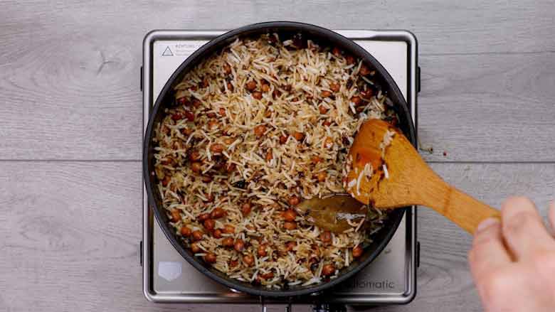 Pour in lime juice and reserved chana cooking water - Kala Chana Pulao Recipe