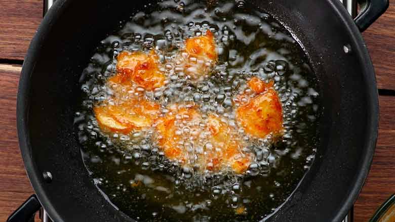 Fry chicken till golden brown then remove with a slotted spoon - Chicken 65 Recipe 