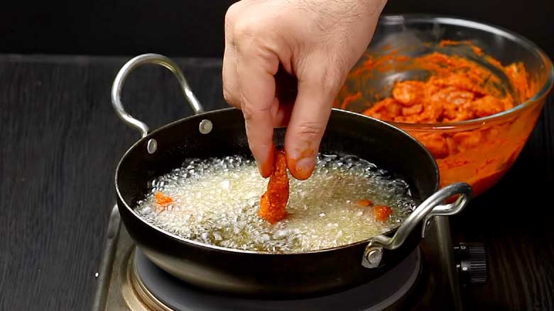 Heat oil, preferably coconut oil, in a kadhai or chatti, and carefully place the marinated chicken pieces in the hot oil in small batches - Kerala Chicken Fry Recipe