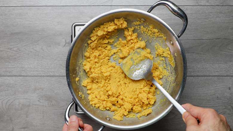 Continue cooking, stirring and scraping the bottom of the pan to ensure the mixture does not catch, till the besan ka prashad separates completely into small granules - Besan Prasad Recipe