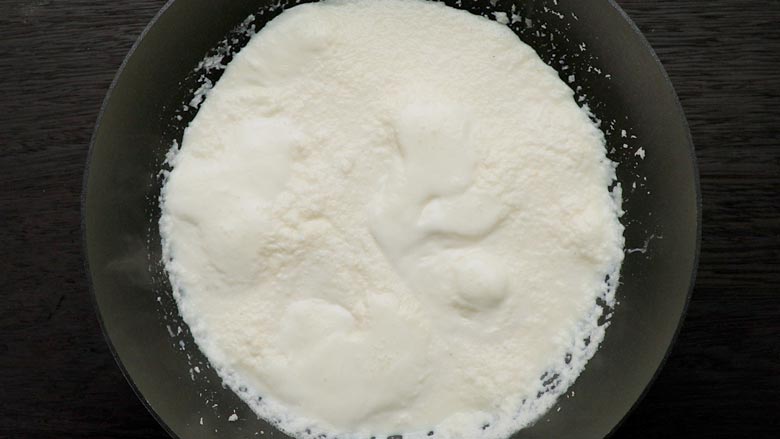 Pour in milk, stir, and bring to a boil - Coconut Ladoo Recipe