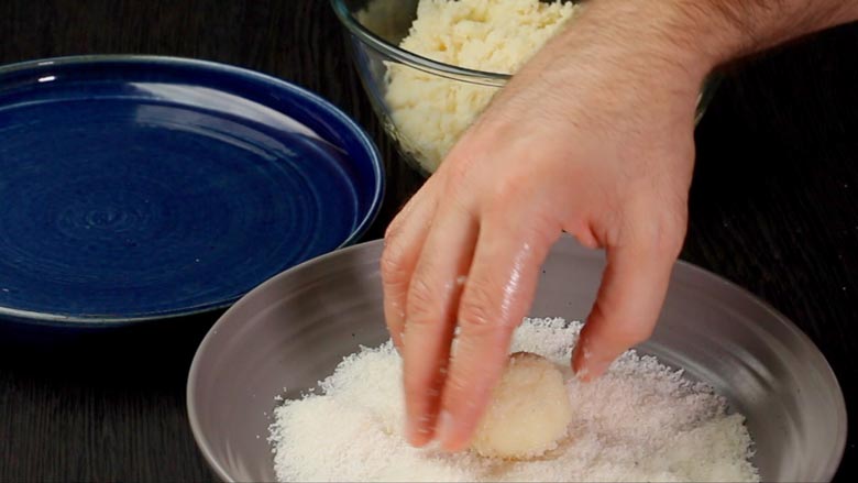 Roll the prepared ladoo in desiccated coconut to coat evenly - Coconut Ladoo