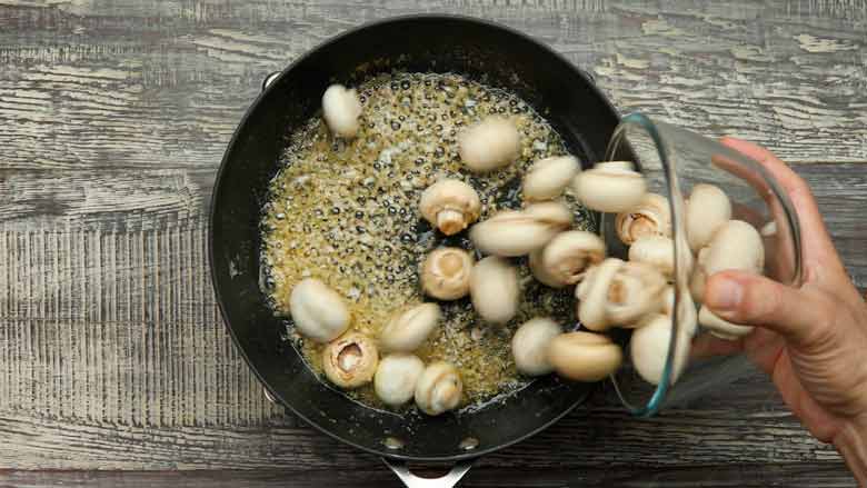 Add cleaned and trimmed button mushrooms to the pan - Garlic Butter Mushrooms Recipe