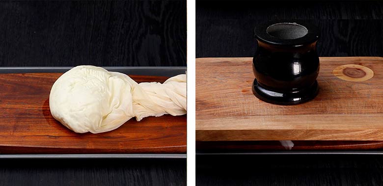Place cloth pouch on a draining board or cutting board and place under a flat plate or board weighed down by a weight such as a heavy pan or a large stone pestle for 5 to 7 minutes - How to make paneer at home from milk