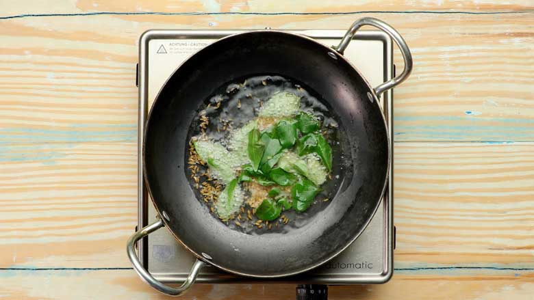 Pour oil into a small kadhai and add black gram (urad dal), cumin seeds, ghee, and curry leaves for tempering - Mixed Vegetable Kootu Recipe