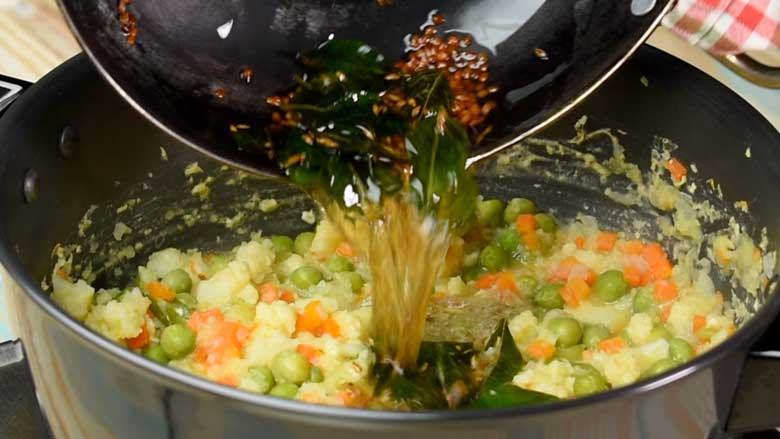 Pour tempered spices and oil over veg kootu and mix well - Mixed vegetable Kootu Recipe