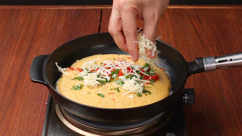Sprinkle fillings - onion, tomato, green chillies, cheese, coriander cheese - on to the cooking omelette - Masala Omelette Recipe