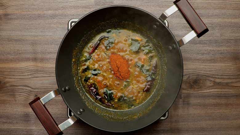 Adding roasted spice masala powder to the sauce and allowing it to thicken for Tamarind Rice - Puliyodhare