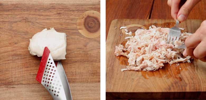 Poached or boiled chicken placed on a wooden cutting board and then shredded using two forks for easy chicken salad