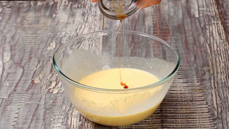 Vanilla extract being added to the cheesecake batter in a glass bowl for Cheesecake Brownies