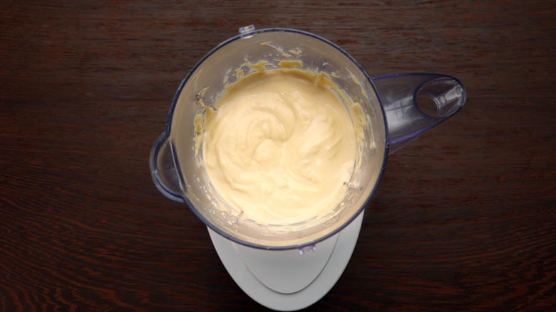 Top view of hummus blended till smooth in a blender on a wooden table