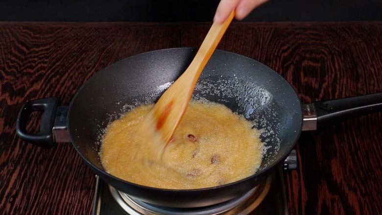 A wooden spatula continues to stir the suji ka halwa in a black kadhai which is thickening to the desired consistency and is nearly ready - Suji Halwa recipe 
