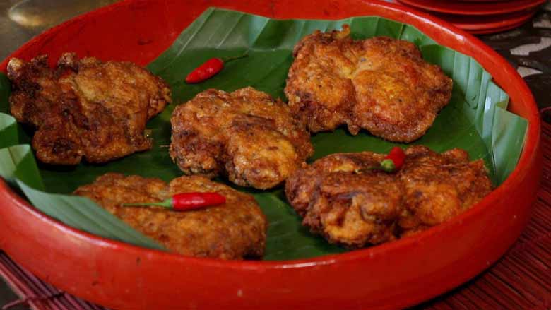 Parsi style Crispy fried chicken pieces garnished with red whole chillies served on a banana leaf in a Burmese lacquer platter - Chicken Farcha Recipe