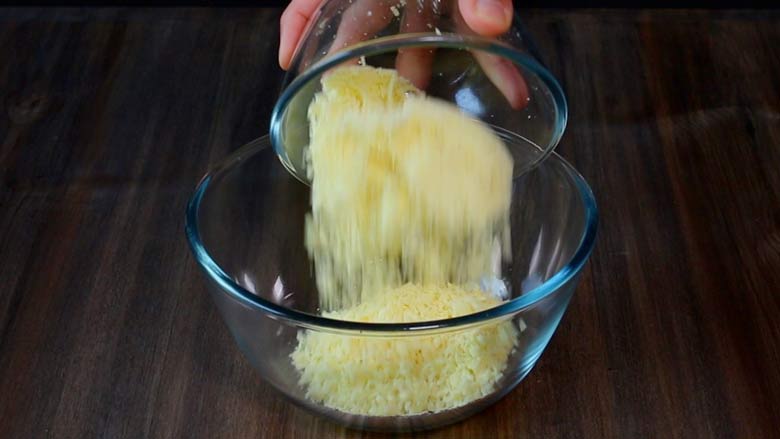 Adding khoya to a glass bowl lying on a dark wooden table while preparing to make gulab jamun - Gulab Jamun recipe with Khoya