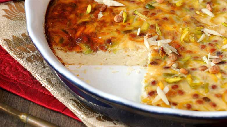 A baked custard in a blue and white baking dish is seen with a large wedge missing. The dense creamy inner of the baked custard can be seen - Lagan Nu Custard Recipe
