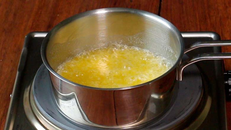 Butter is melting and bubbling away in a stainless steel saucepan on a metallic electric stove on its way to browning - Pasta with Herb Butter Sauce Recipe