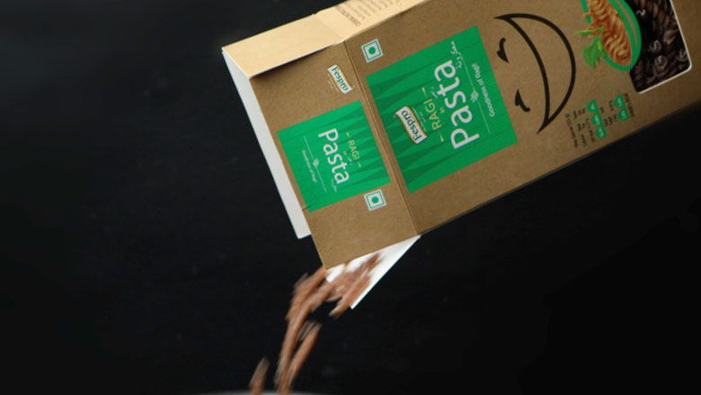 A box of Fespro Ragi Pasta has been opened and tilted to to empty out the fusilli pasta into boiling water - Pizza Sauce Pasta Recipe